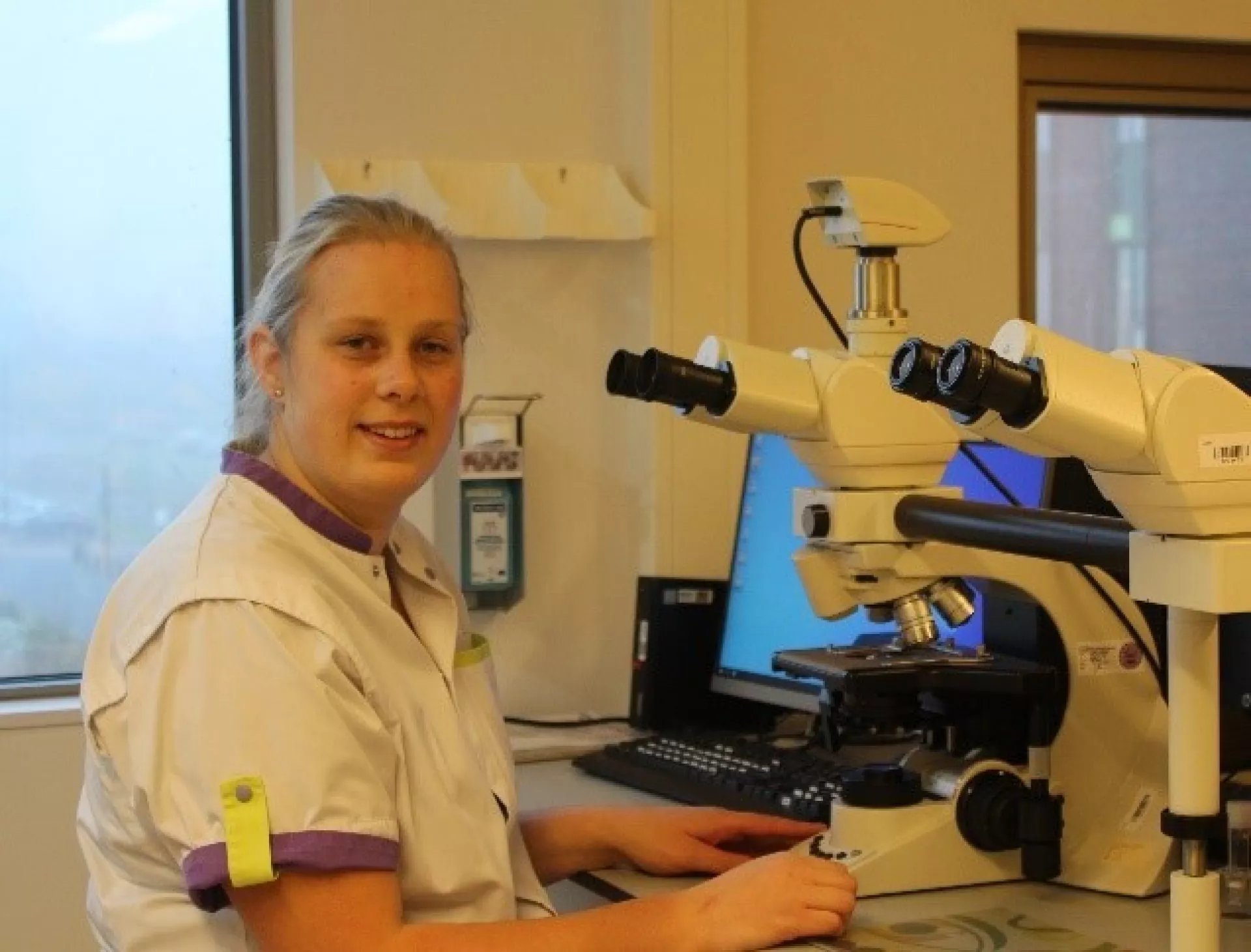 Jorien Wierenga analist klinische chemie bij microscoop in labjas