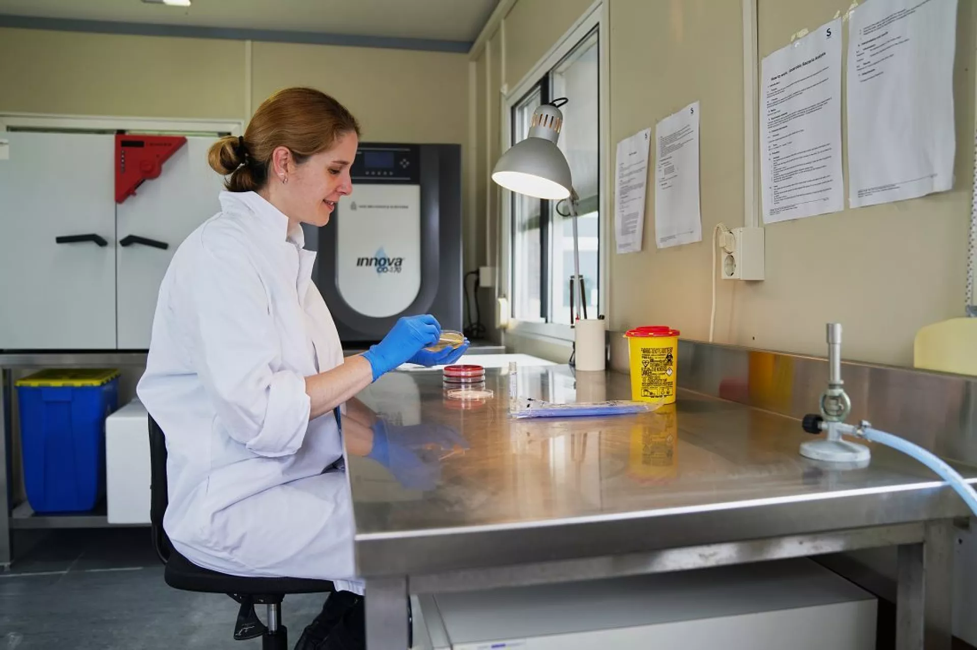 Ana Rubio Garcia bij tafel in labjas met blauwe handschoen