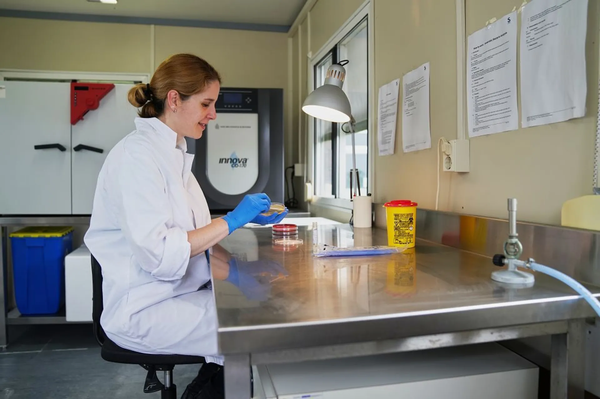 Ana Rubio Garcia bij tafel in labjas met blauwe handschoen