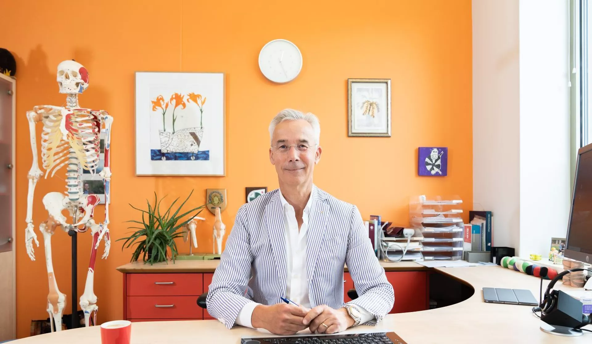 Sander Jonges huisarts aan bureau voor oranje wand