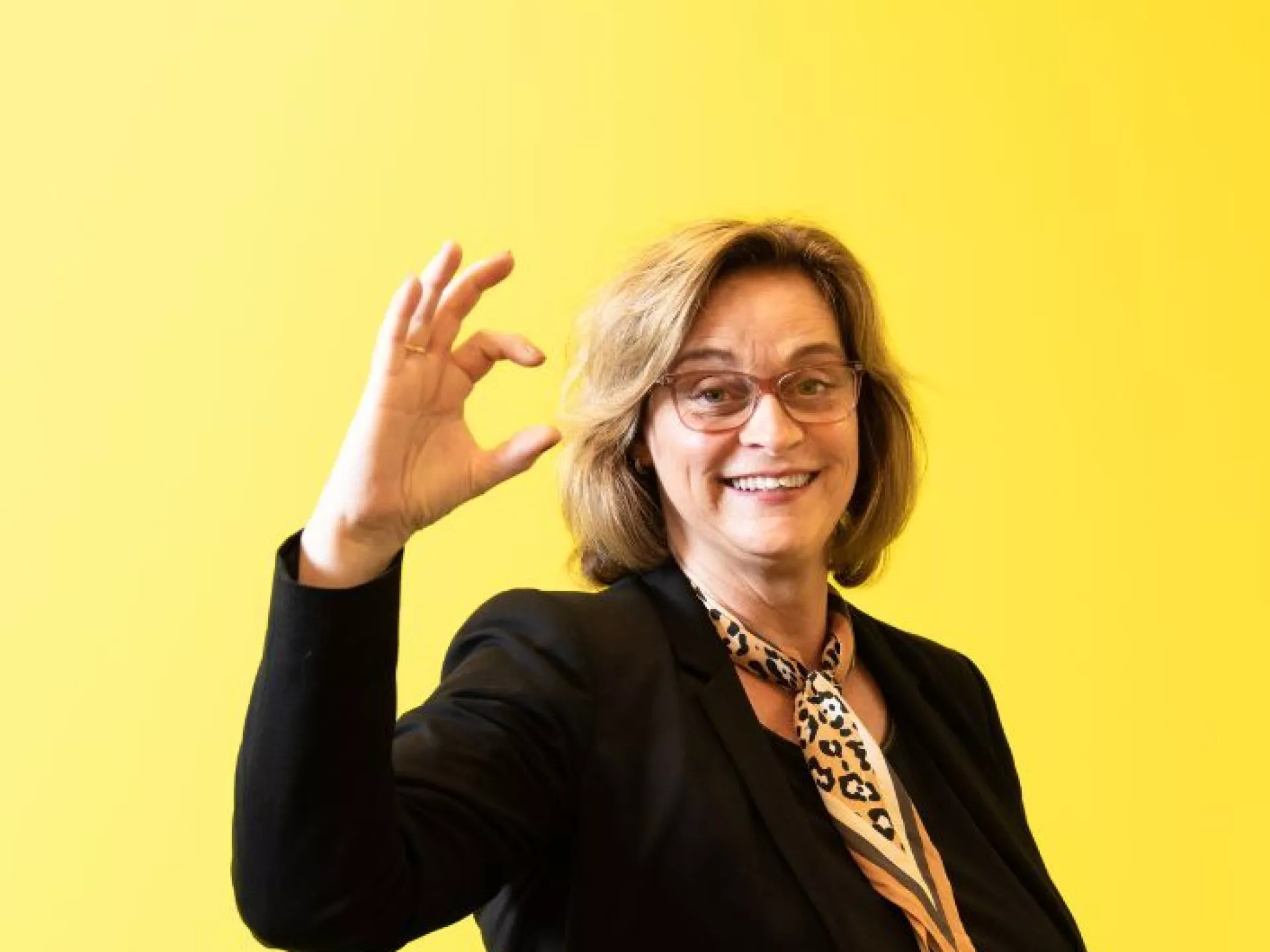 Dame voor gele wand met zekerCerte gebaar