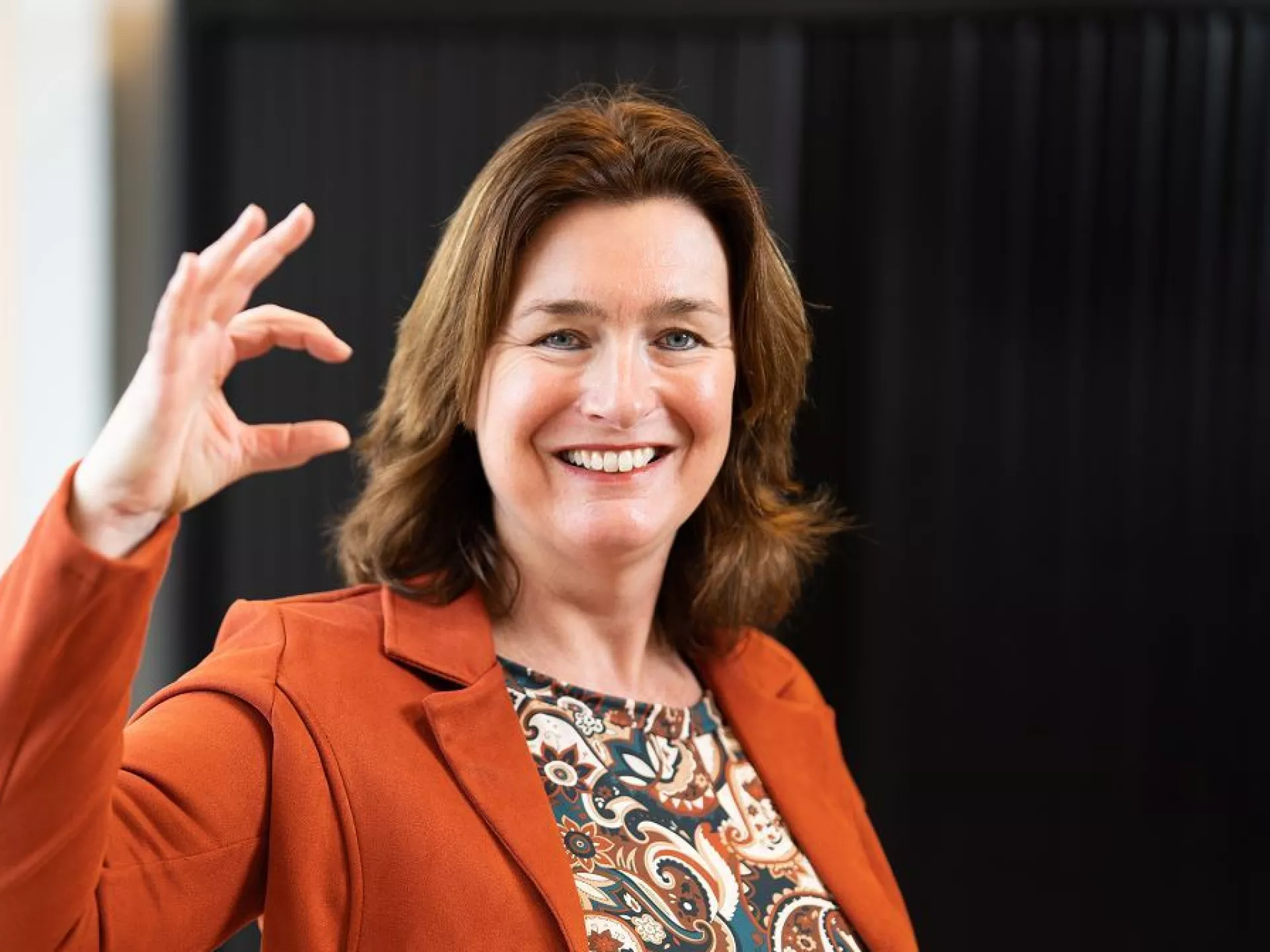 Dame voor zwarte wand met zekerCerte gebaar