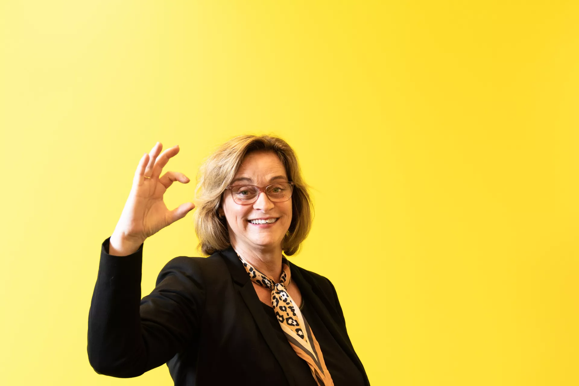 Dame voor gele wand met zekerCerte gebaar