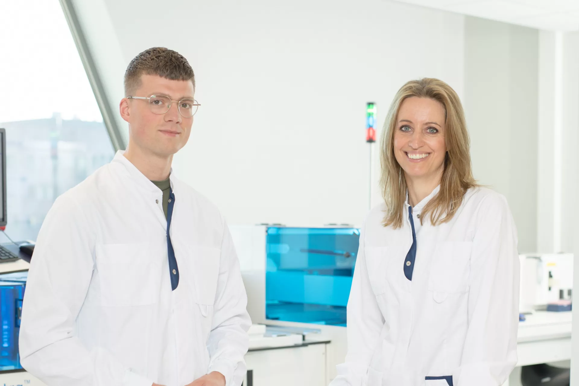 Man en vrouw analisten medische microbiologie in labjas bij rekje buizen