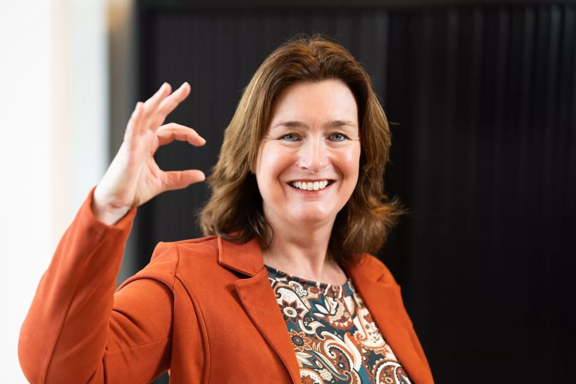 Dame voor zwarte wand met zekerCerte gebaar