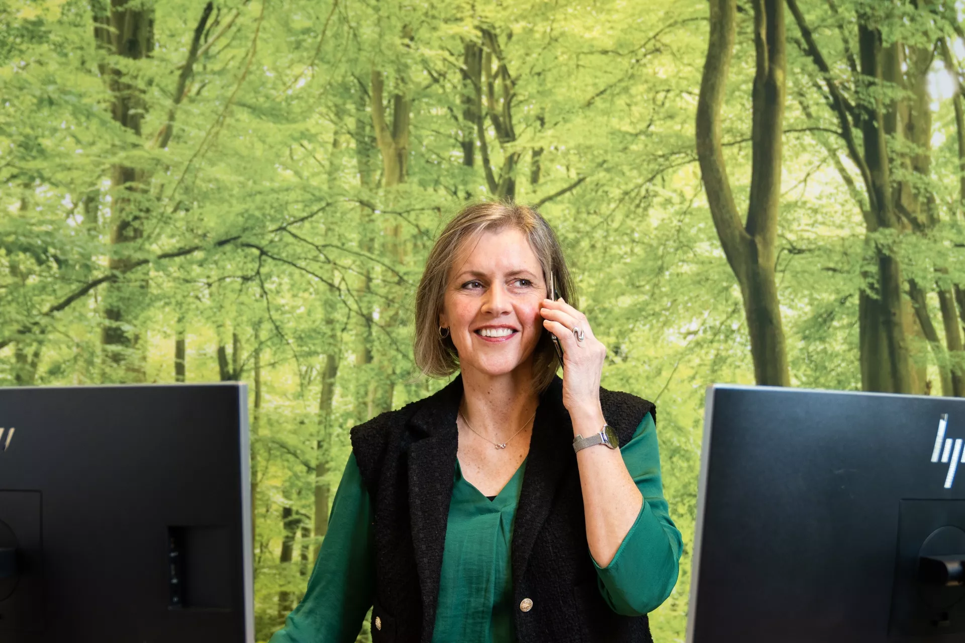 Dame bellend met telefoon voor twee computerschermen