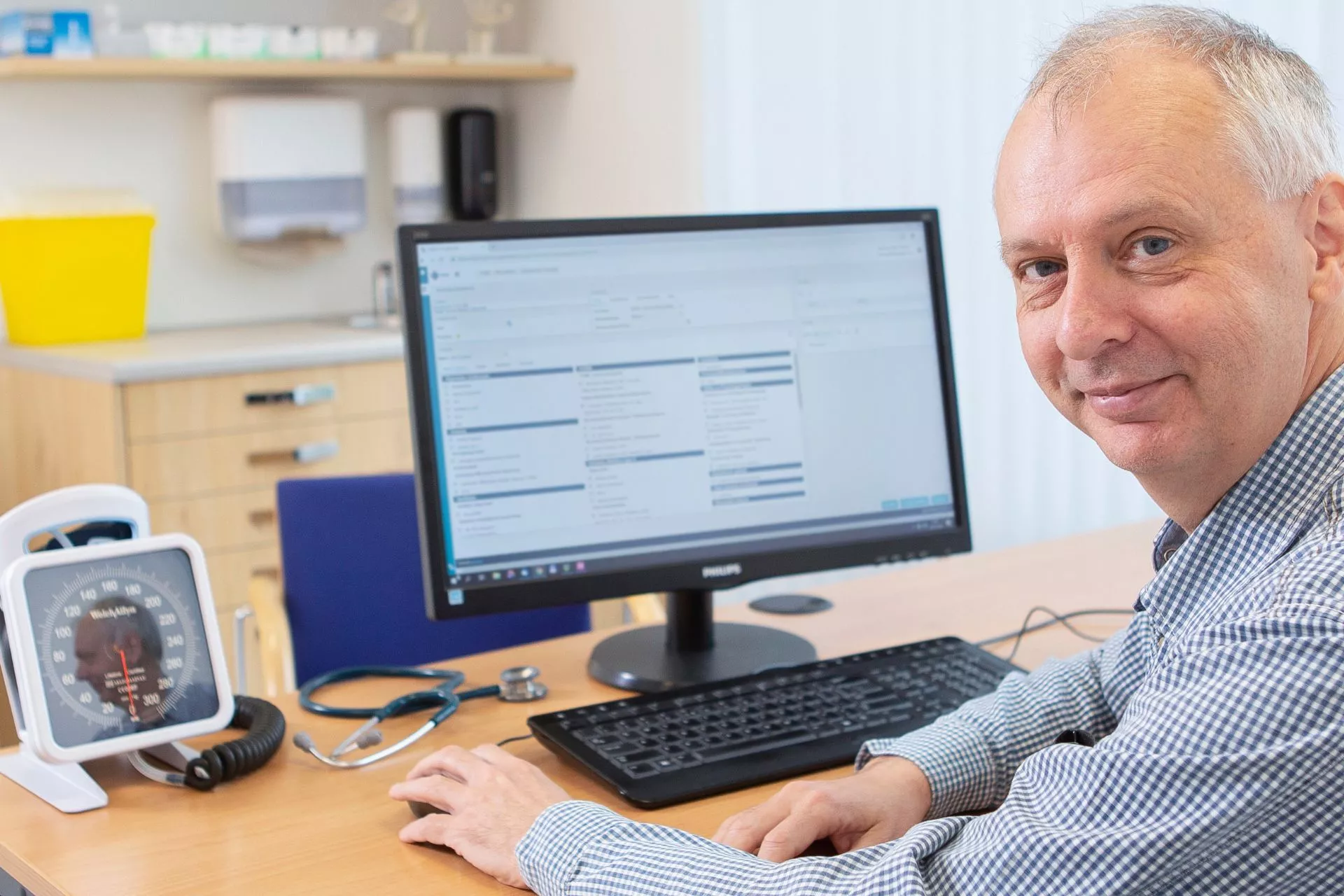 Huisarts man voor computerscherm aan bureau