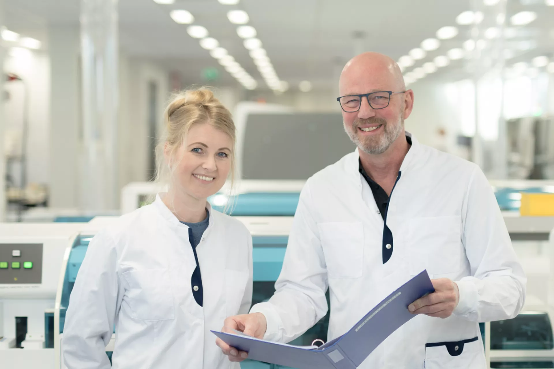 Man en vrouw op laboratorium in labjas met map in handen