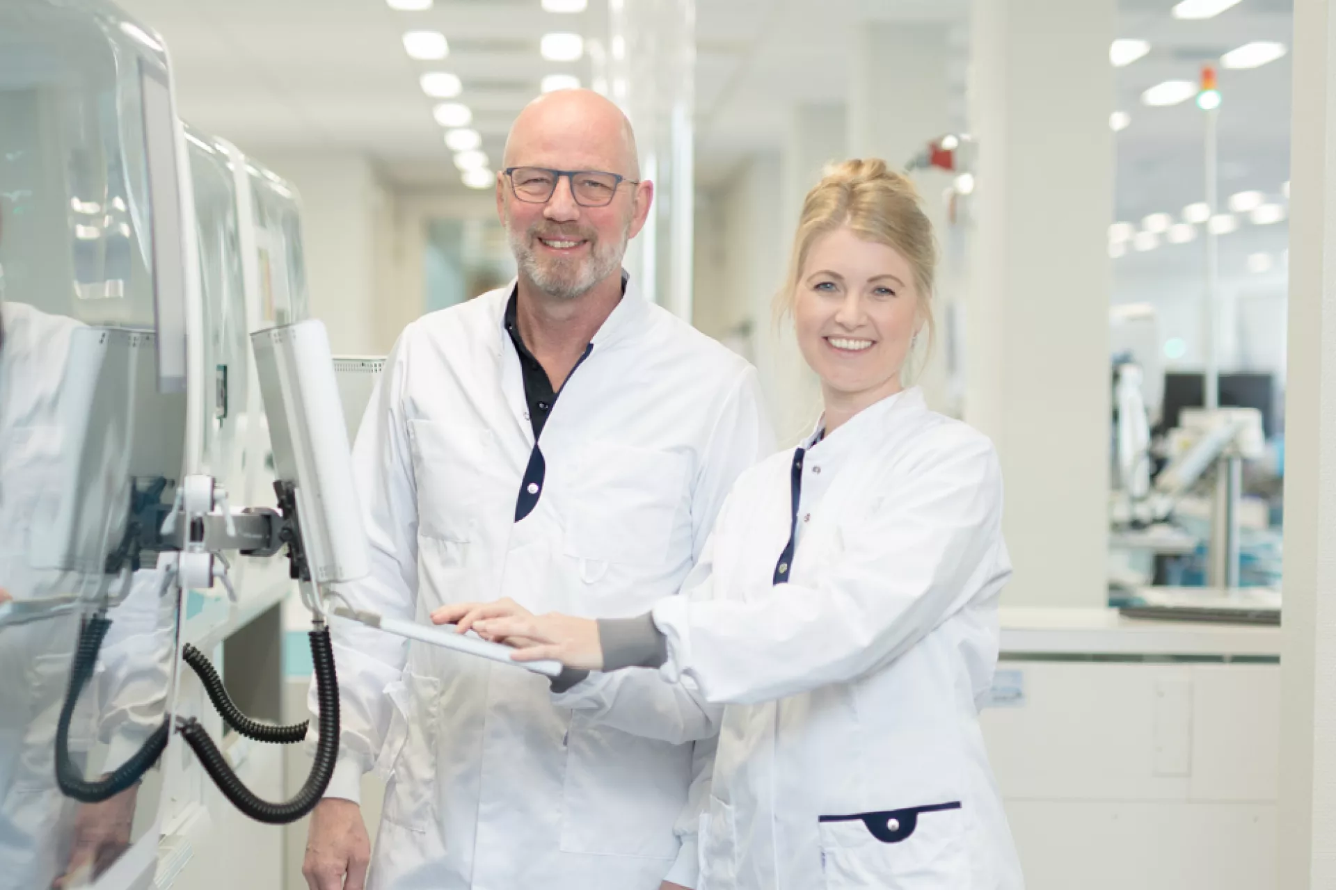 Klinisch chemici man en vrouw in labjas op laboratorium naast apparatuur