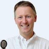 Portret Henk Kramer met stethoscoop voor witte wand